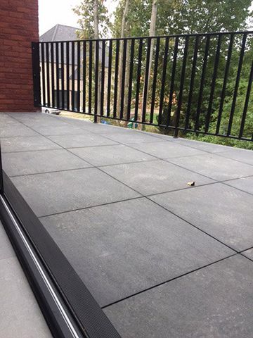 Terras in grootformaat tegels langs een zwart hekwerk