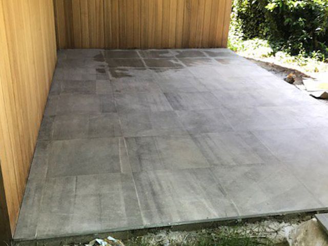 Terras in grote tegels naast een houten schutting