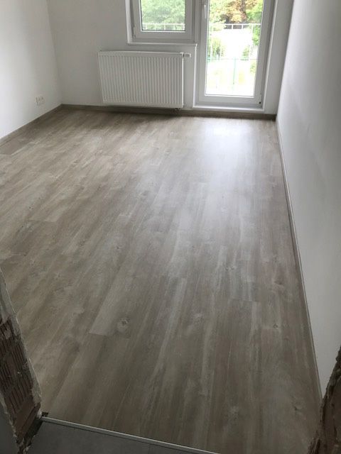 Vloer met houtmotief in een lichte kamer met witte plinten